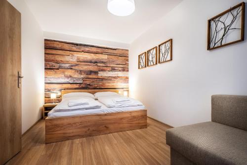 a bedroom with a bed with a wooden wall at Apartmánový dom Štiavnica in Liptovský Ján