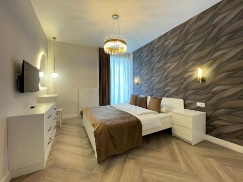 a bedroom with a bed and a tv and a wall at Apartment No 503 Lebada Lake Residence in Pantelimon