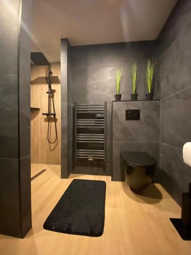 a bathroom with a black toilet and plants on the wall at Suite LIANA - SPA- SAUNA in Rorschwihr