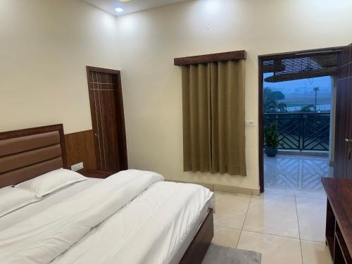a bedroom with a bed and a door to a balcony at SS Farms Hotel & Resort in Sonīpat