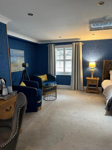 a bedroom with blue walls and a bed and a chair at Derby Manor in Bournemouth