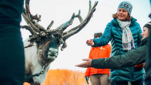 a woman is standing next to a reindeer at Lyngenfjord Hotel in Skibotn