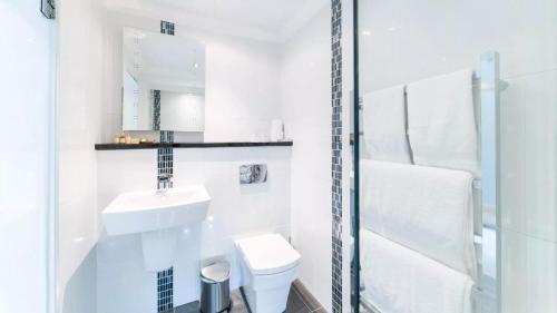 a white bathroom with a sink and a toilet at Derby Manor in Bournemouth