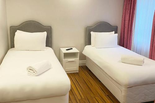 two beds in a small room with white sheets at Bluewaters Hotel Blackpool in Blackpool