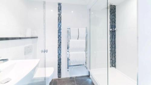a white bathroom with a sink and a shower at Derby Manor in Bournemouth