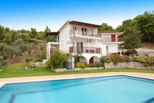 a villa with a swimming pool in front of a house at Villa Alissia in Koukounaries