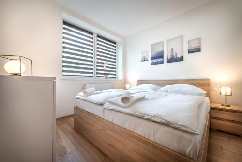 a bedroom with a bed with white sheets and a window at Apartmánový dom Štiavnica in Liptovský Ján