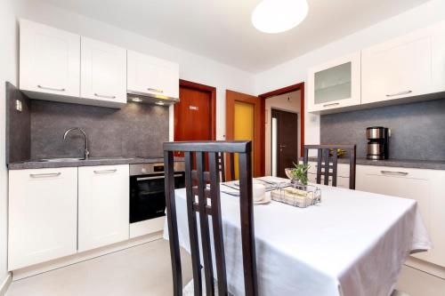 eine Küche mit weißen Schränken und einem weißen Tisch in der Unterkunft Apartments Carmelo in Rovinj