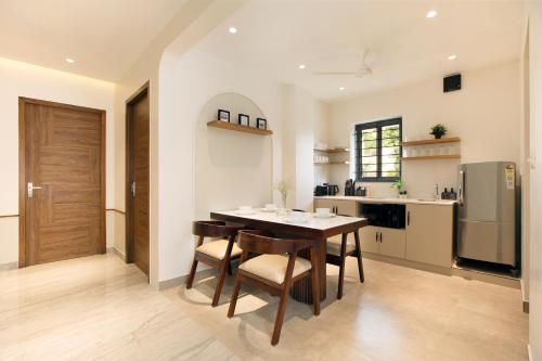 a kitchen with a table and chairs and a refrigerator at The Madras Grand in Chennai