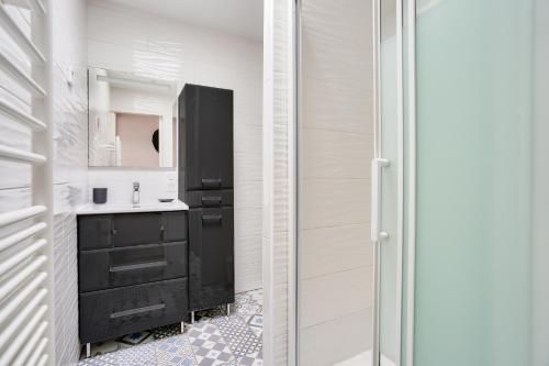 a bathroom with a black vanity and a mirror at À 200m de la plage, maison cosy pour 4 in Dinard