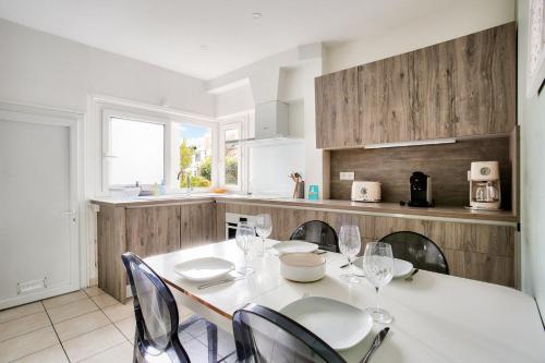 une cuisine avec une table et des chaises blanches, une table et des chaises dans l'établissement À 200m de la plage, maison cosy pour 4, à Dinard
