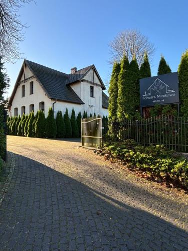 a white house with a sign in front of a driveway at Folwark Minikowo - Agroturystyka w Borach Tucholskich - 5 pokoi z prywatnymi łazienkami in Bysław