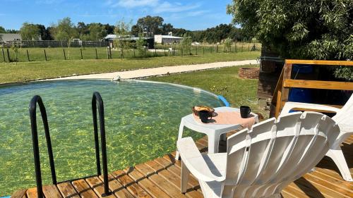 a table and a chair next to a swimming pool at Playa & Campo - Experiencia Glamping en Mar de Ajó in Mar de Ajó
