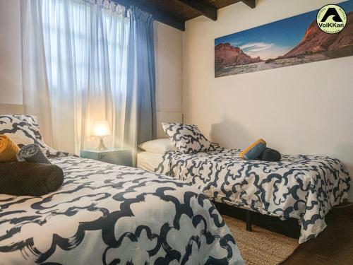 ein Schlafzimmer mit zwei Betten und einem Fenster in der Unterkunft VolKKanrentals Casa La Hoya in Famara