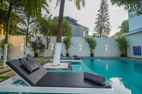 a pool with two lounge chairs next to a building at EKOSTAY Gold - Driftwood Villa in Alibaug