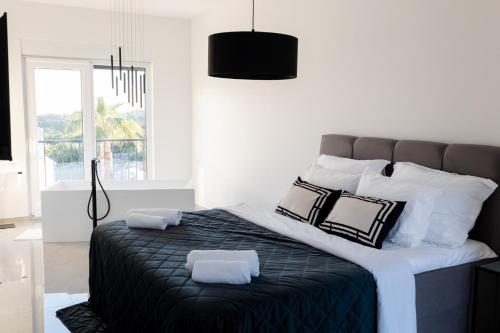 ein Schlafzimmer mit einem großen Bett mit schwarzen und weißen Kissen in der Unterkunft Villa Koko Vinišće with heated pool and sea view in Vinišće