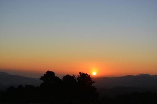 a sunset over the mountains with trees in the foreground at Finca Paraiso Mountain Retreat near San Jose Airport in Birrí