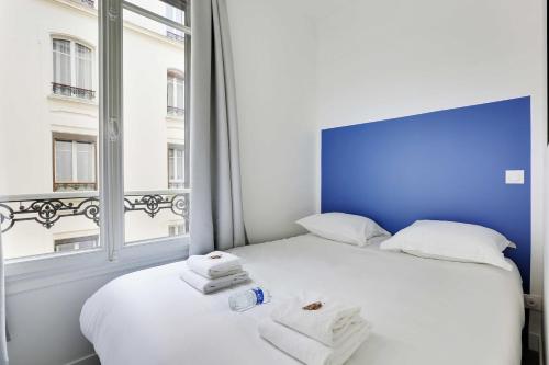 une chambre avec un lit blanc avec des serviettes dessus dans l'établissement Charming Apartment -1BR-4P- Château de Vincennes, à Vincennes