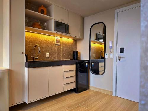 a kitchen with white cabinets and a mirror at Yacht by Hosppedar in João Pessoa