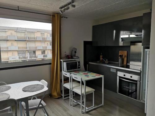 une petite cuisine avec une table et une table et des chaises dans l'établissement Palma Studio bis 4 pers - 100m plage, à Port-la-Nouvelle