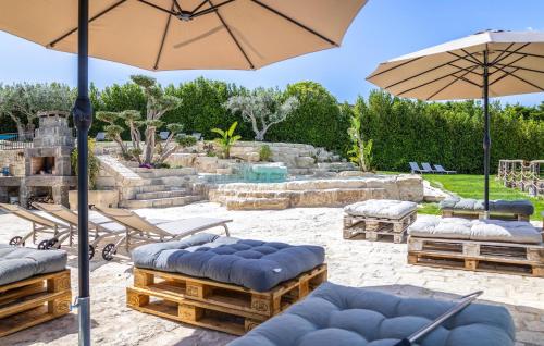 a patio with chairs and umbrellas in a yard at Gorgeous Home In Giarratana in Giarratana