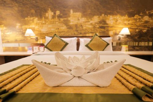 a plate with a flower on top of a bed at Regenta Orko's Haridwar, Motichur, 10 min from Har ki Pauri in Haridwār