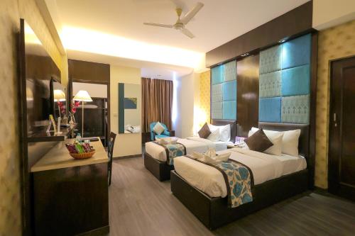 a hotel room with two beds and a desk at Regenta Orko's Haridwar, Motichur, 10 min from Har ki Pauri in Haridwār