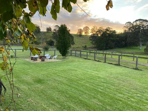 a grassy field with a fence and picnic tables at Little Farmhouse Near The Dairy in Warranulla