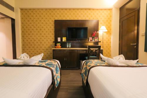 a hotel room with two beds and a television at Regenta Orko's Haridwar, Motichur, 10 min from Har ki Pauri in Haridwār