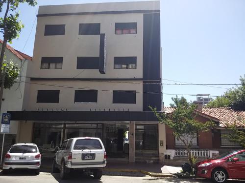 dos coches estacionados frente a un edificio en Hotel Europa en Mar del Plata