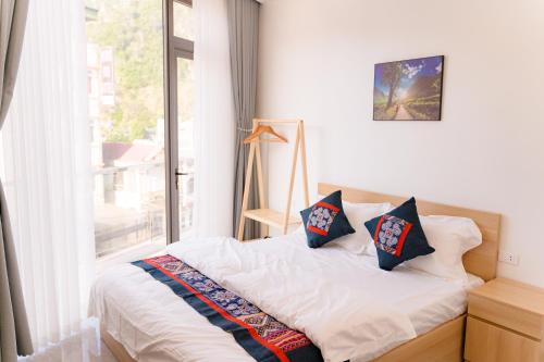 a bedroom with a bed with pillows and a window at Apollo Hotel in Dồng Văn