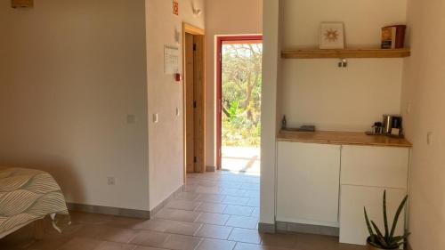 a room with a kitchen with a counter and a door at Choeiro Verde - Casa de Campo na Costa Vicentina in Brejao