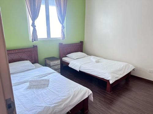 two twin beds in a room with a window at Ubays Zetepark House in Kuala Lumpur
