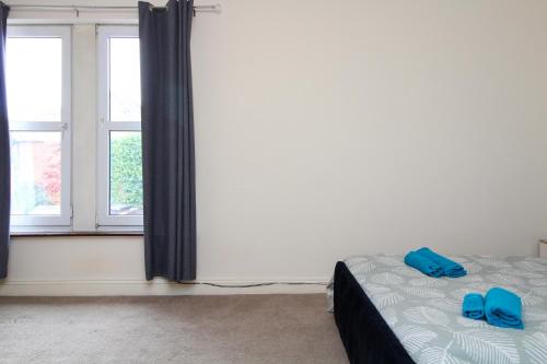 a bedroom with a bed with blue slippers on it at Darwin road guest house 3 in Southampton