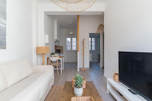 a living room with a white couch and a flat screen tv at Le Pytheas - Nid douillet à deux pas du vieux port in Marseille