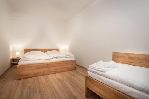 two beds in a room with white walls and wooden floors at Apartmánový dom Štiavnica in Liptovský Ján