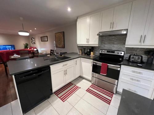 a kitchen with white cabinets and black appliances at Amazing 3-Bedrooms in Rosemont - Montreal in Montréal