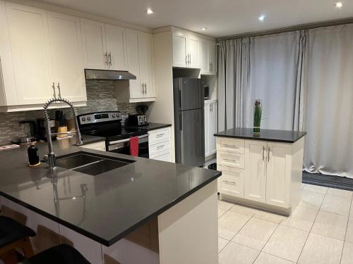 a kitchen with white cabinets and a black counter top at Amazing 3-Bedrooms in Rosemont - Montreal in Montréal
