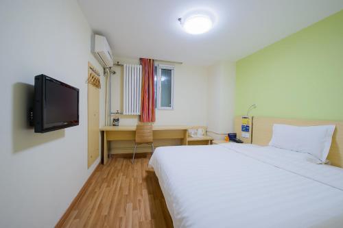 洛陽市にある7Days Inn Luoyang Longmen Avenue Normal Collegeのベッドとテレビが備わるホテルルームです。