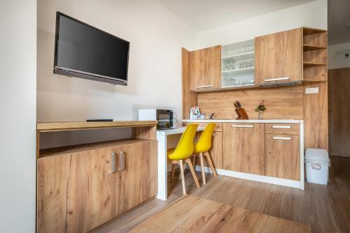a room with a kitchen with a bar with yellow chairs at Apartmánový dom Štiavnica in Liptovský Ján