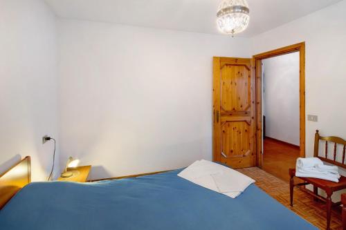 a bedroom with a blue bed and a wooden door at Appartamenti Minotto Falcade in Falcade