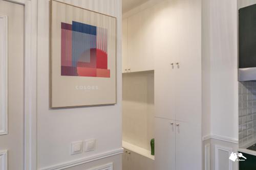 une cuisine avec des placards blancs et un tableau mural. dans l'établissement MBA - Cavalloti Splendide Appartement, à Paris