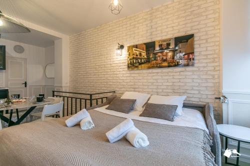 une chambre avec un grand lit et un mur de briques dans l'établissement MBA - Cavalloti Splendide Appartement, à Paris
