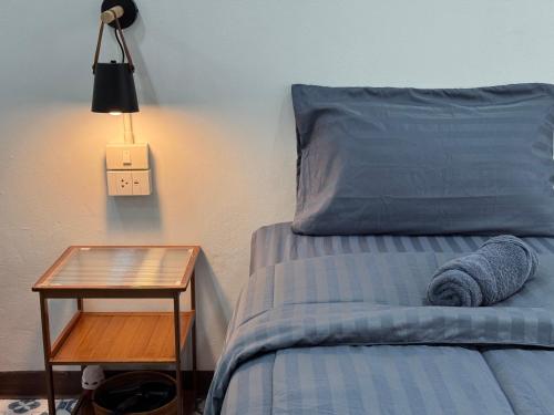 a bed with a night stand next to a bed with a blue pillow at Nut Home Hostel in Ban Ko
