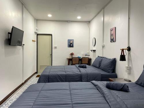 a room with two beds and a television in it at Nut Home Hostel in Ban Ko