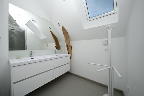 a white bathroom with a sink and a mirror at La maison Poulogne in Capvern