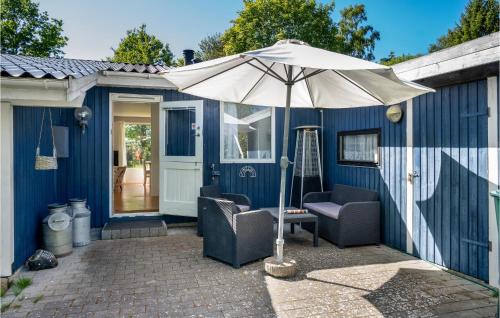 a blue house with two chairs and an umbrella at Awesome Home In Grevinge With Wifi in Grevinge