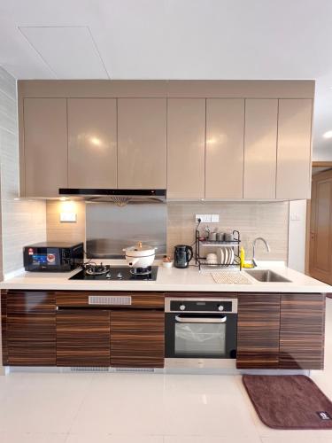 a kitchen with wooden cabinets and a stove and a sink at R&F Princess Cove View Residences by WSD in Johor Bahru