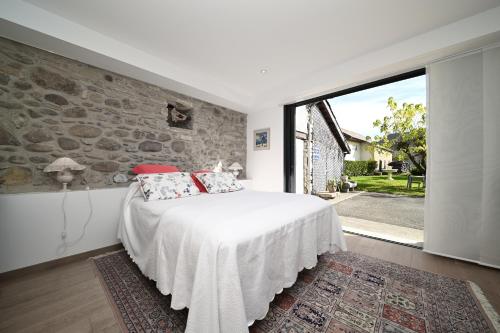 a bedroom with a white bed and a stone wall at La maison Poulogne in Capvern
