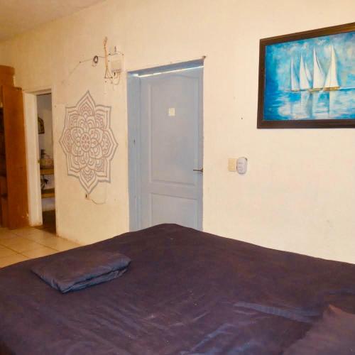 a bedroom with a bed and a painting on the wall at Hostalito Lahar in Bacalar